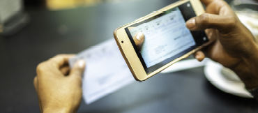 Image of a person taking a pictures of a check with their phone.