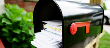 Image of an open black mailbox full of mail.