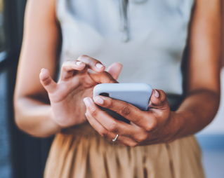 Image of person holding a cell phone in their hands in front of their body.